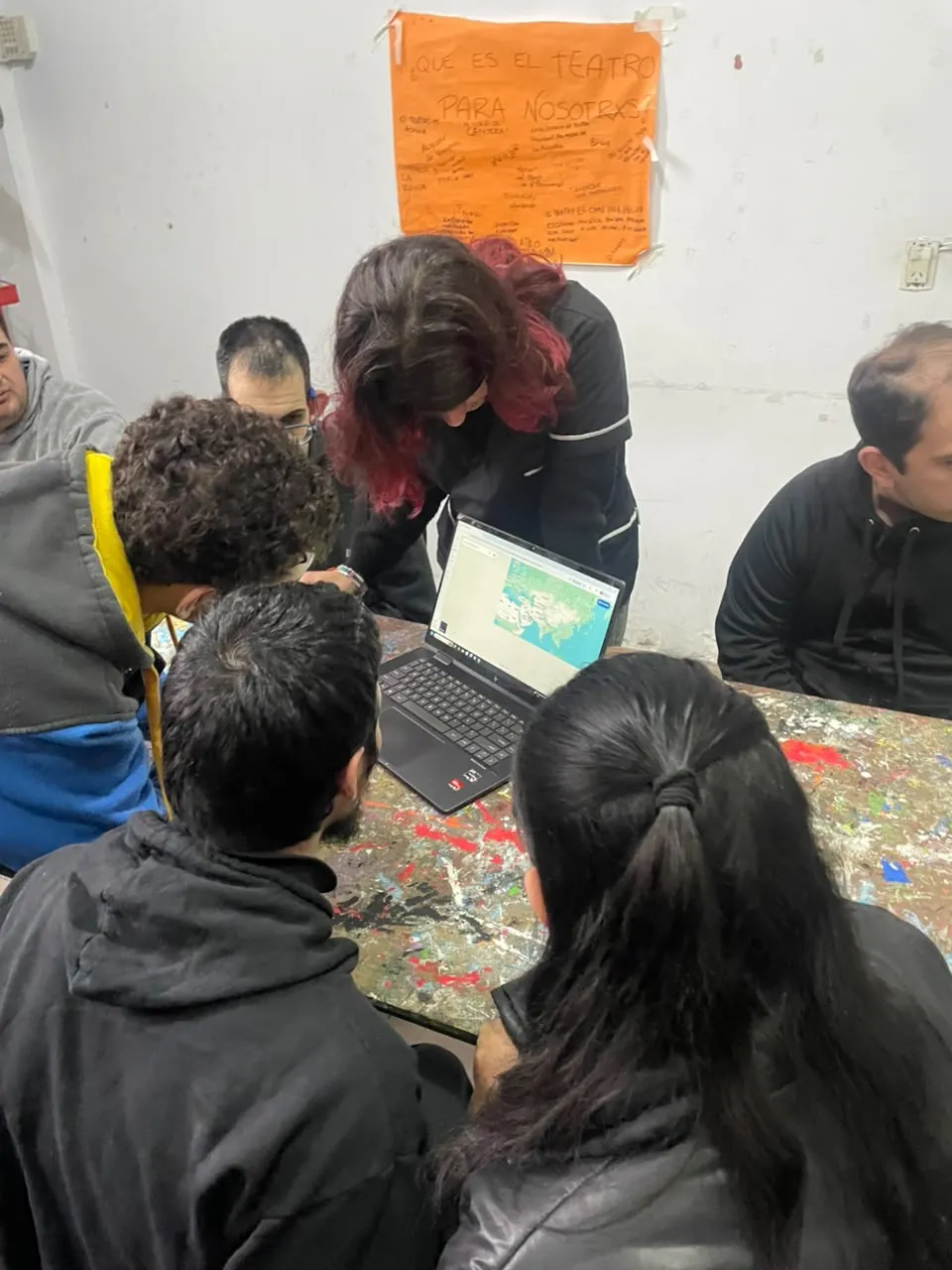 Concurrentes reunidos alrededor de una notebook durante el taller de periodismo